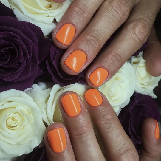 Orange Maniküre zwischen Rosen