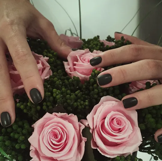 Dunkle Maniküre zwischen rosa Rosen
